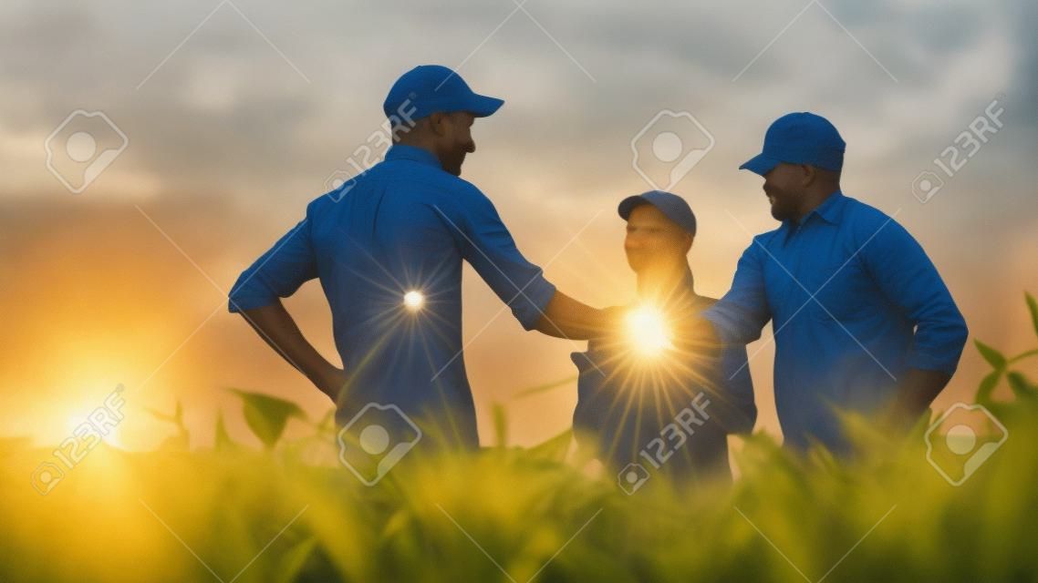 Um grupo de agricultores no campo, apertando as mãos. Família Agronegócio