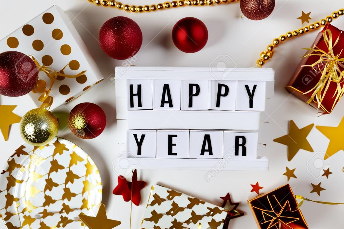 Neujahr 2021 festliche Tischdekoration, Party. Weihnachtsgoldsterne, festliche Pappteller und -gläser, mehrfarbige Herzen, goldene Konfettisterne auf weißem Hintergrund