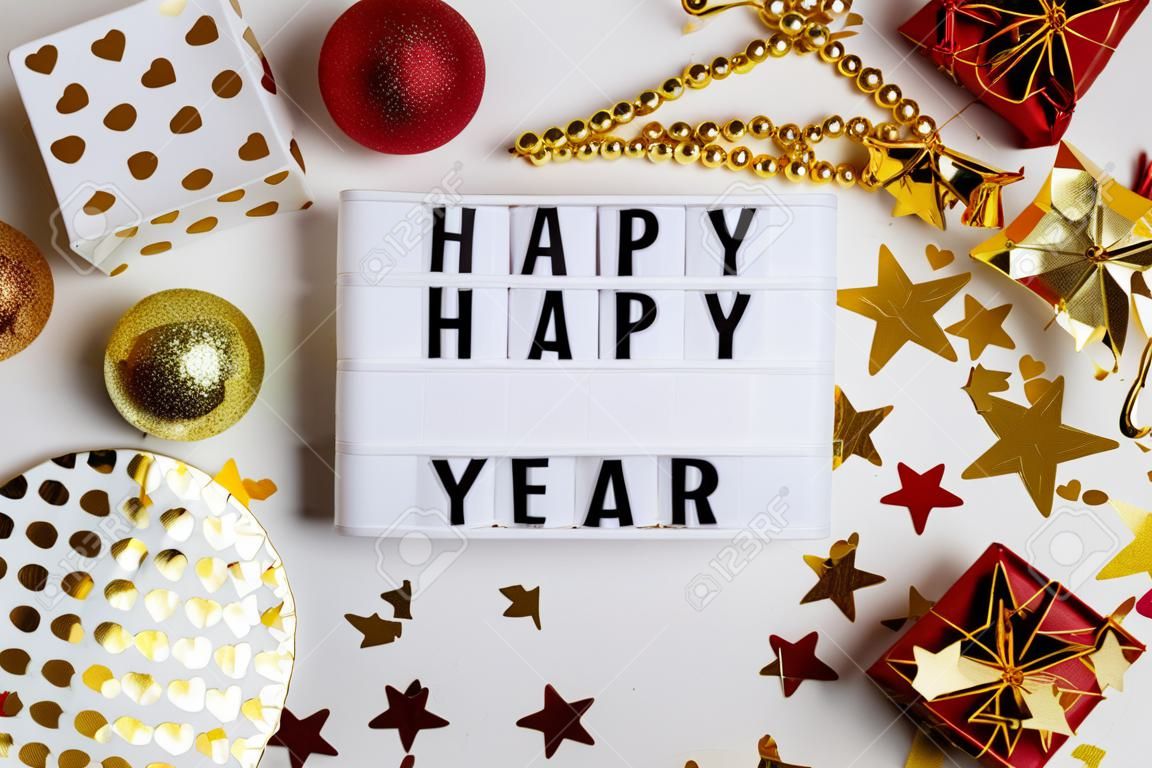 Neujahr 2021 festliche Tischdekoration, Party. Weihnachtsgoldsterne, festliche Pappteller und -gläser, mehrfarbige Herzen, goldene Konfettisterne auf weißem Hintergrund