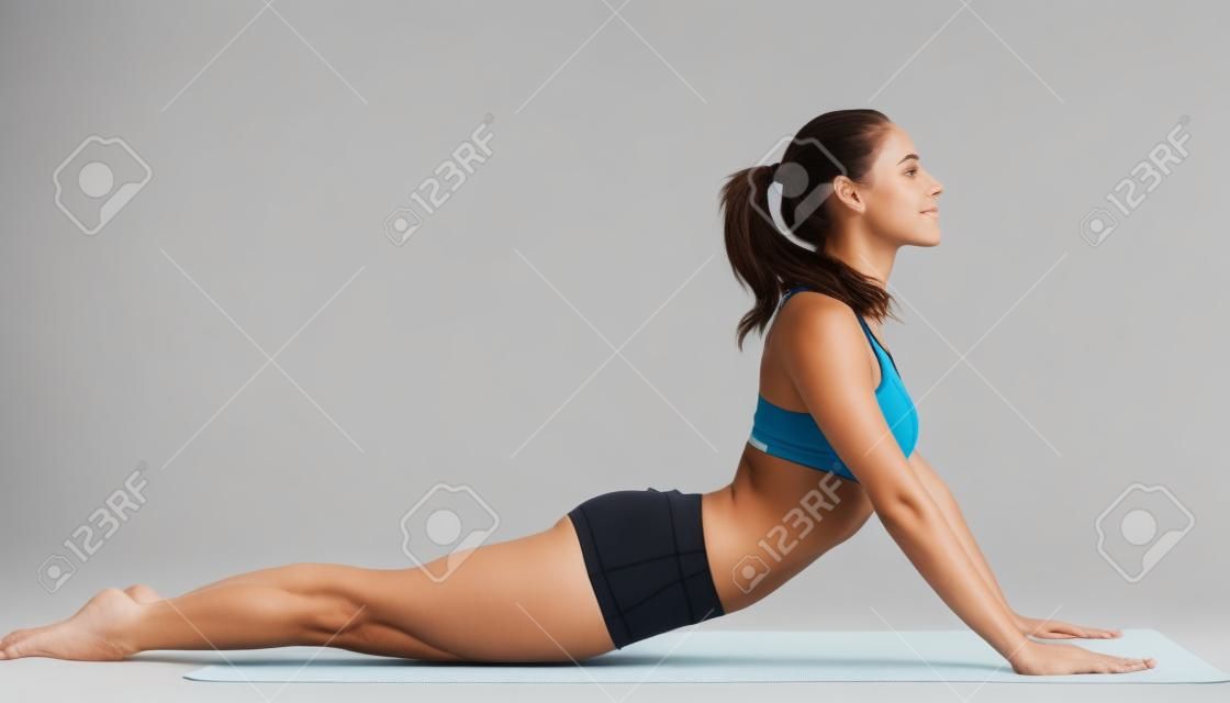 junge Frau im Sport-BH für Yoga-Pose auf weißem Hintergrund isoliert
