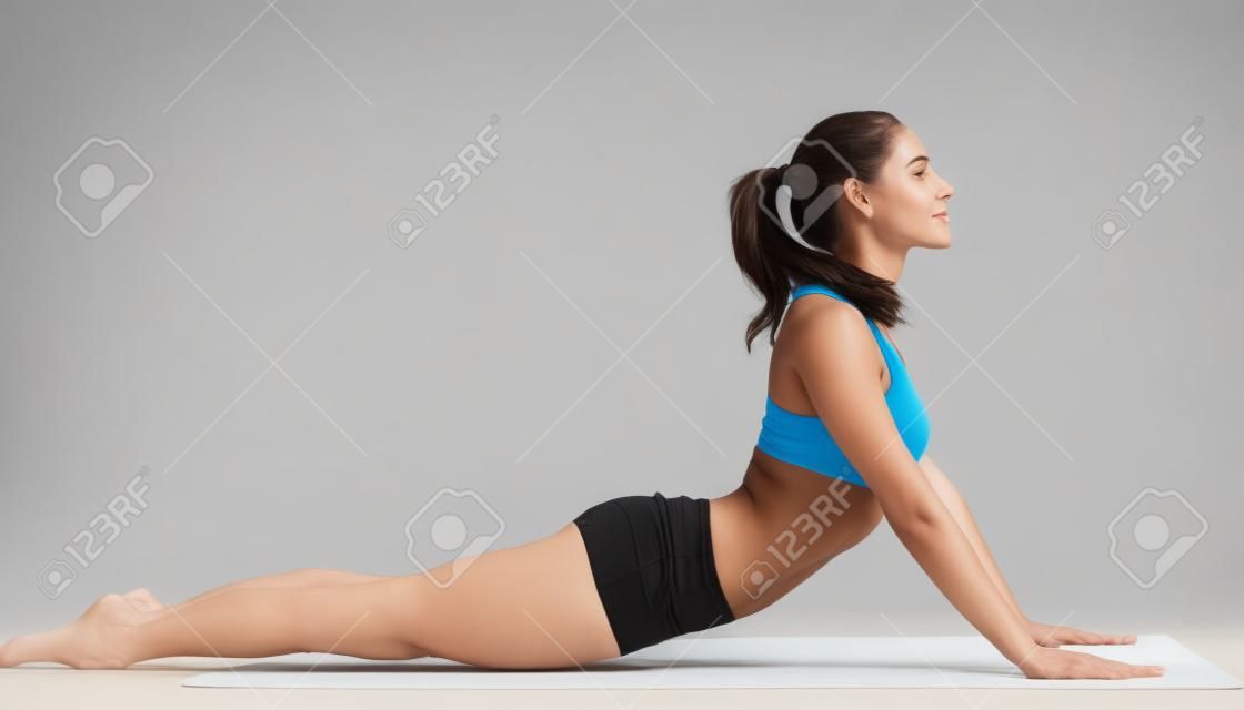 junge Frau im Sport-BH für Yoga-Pose auf weißem Hintergrund isoliert