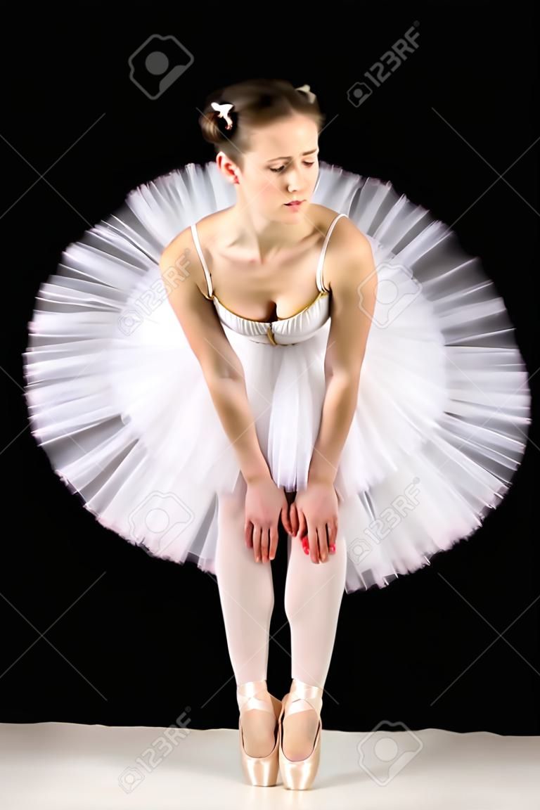 classical ballerina in a white skirt over black background