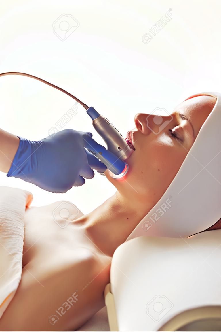 Young woman getting ultrasound skin cleansing and face treatment at beauty salon