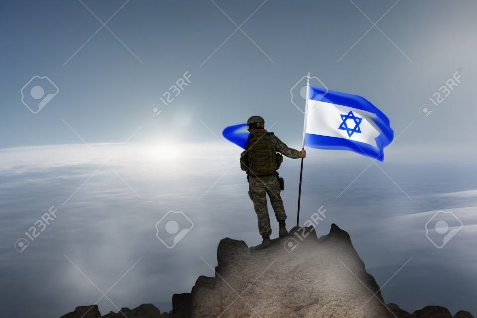 Soldado en la cima de la montaña con la bandera israelí
