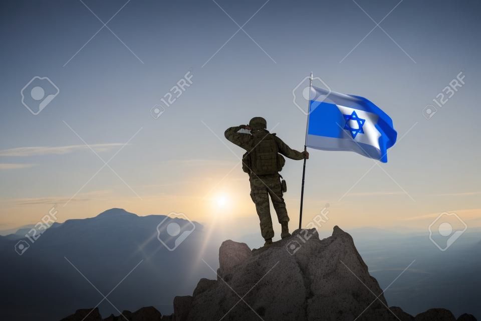 Żołnierz na szczycie góry z flagą Izraela