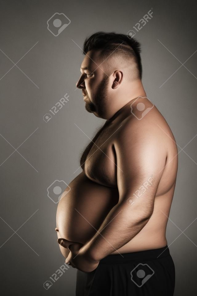 kövér félmeztelen férfi pózol a stúdióban