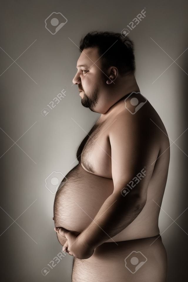 kövér félmeztelen férfi pózol a stúdióban