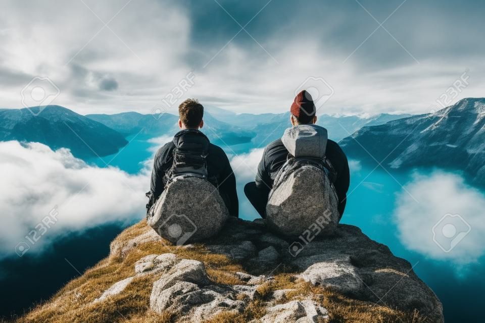Dwóch mężczyzn cieszących się widokiem ze szczytu góry odpowiednim do tematów podróży i przygód