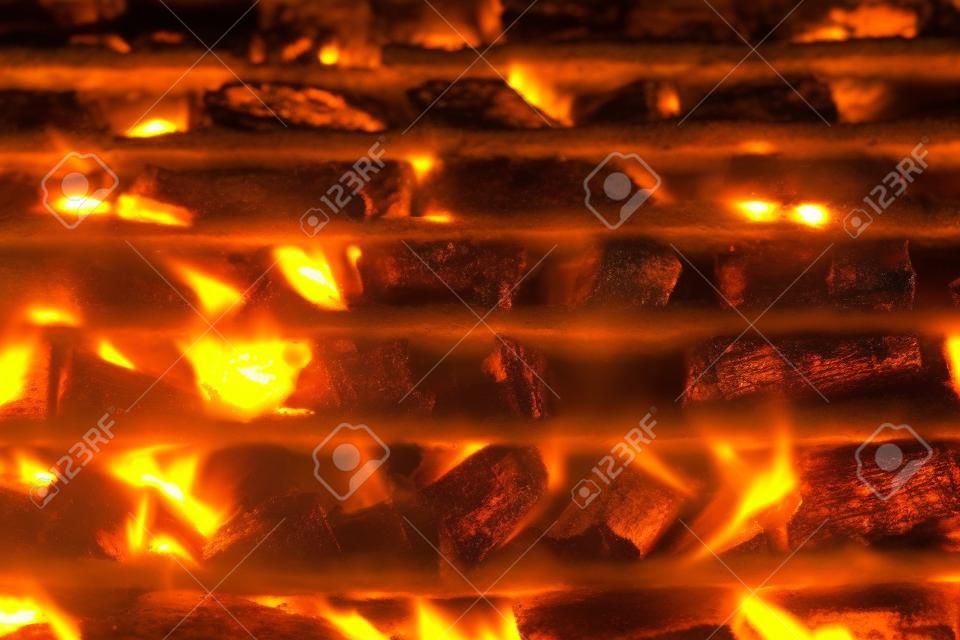 Barbecue grill pit with glowing and flaming hot charcoal briquettes