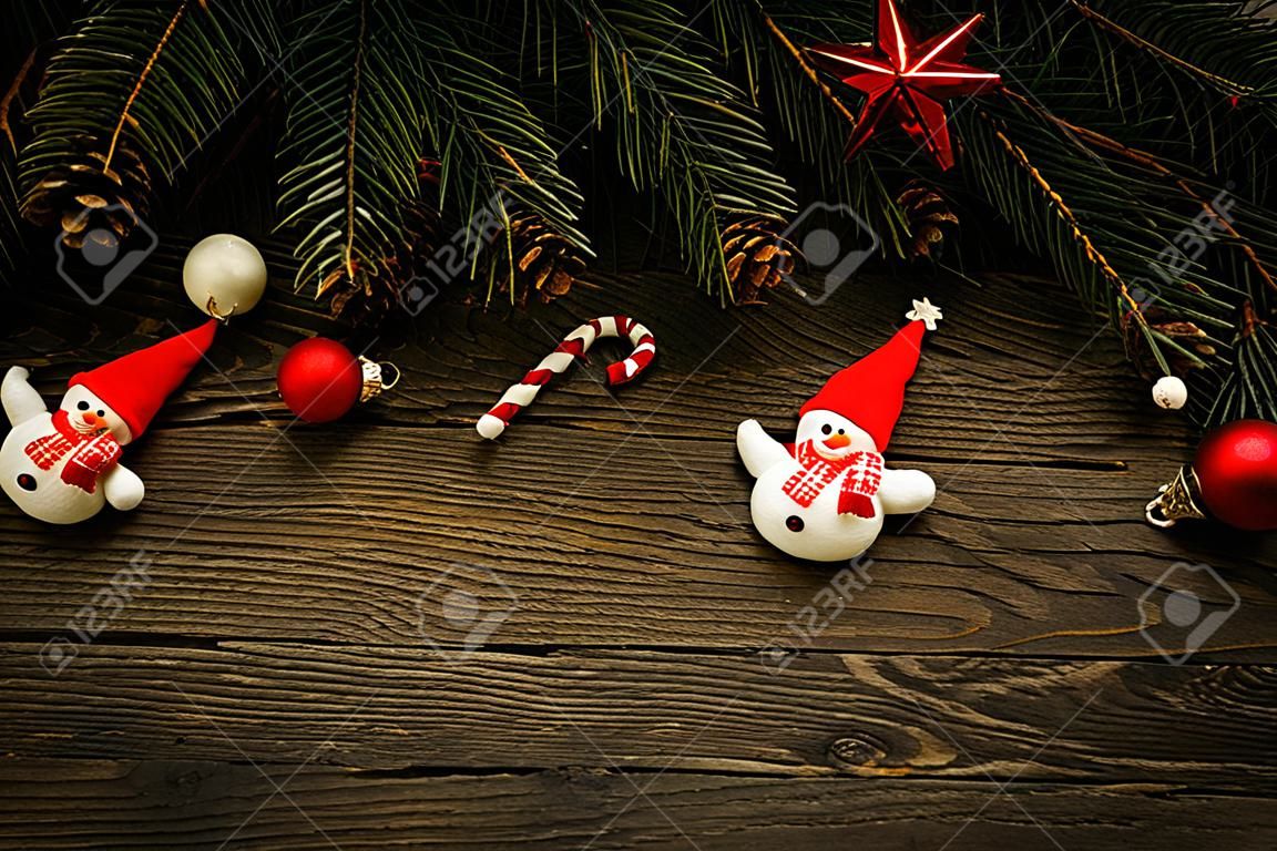 Christmas tree branches with christmas decorations and snowman on wooden texture.