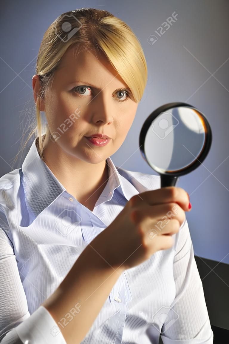 The beautiful blonde woman in blue shirt and with magnifying glass