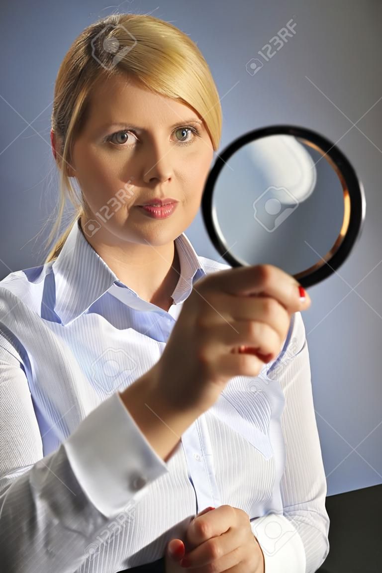 The beautiful blonde woman in blue shirt and with magnifying glass