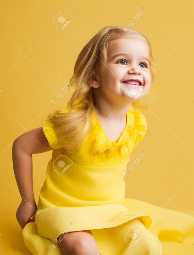 スマイリー白い背景の上に座っている黄色のスカートを着て幸せな女の子