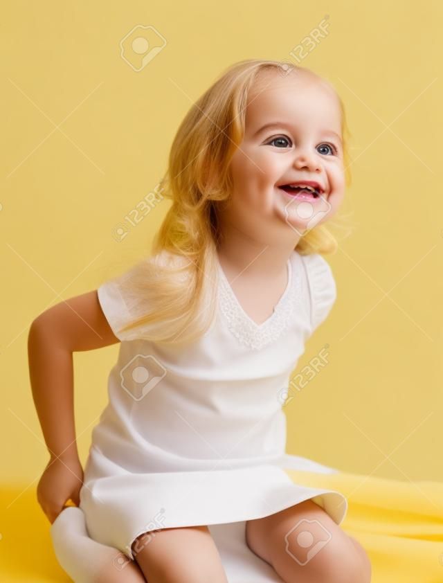 スマイリー白い背景の上に座っている黄色のスカートを着て幸せな女の子