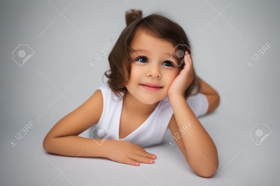 Little girl lying on the floor, looking up and dreaming on white  background
