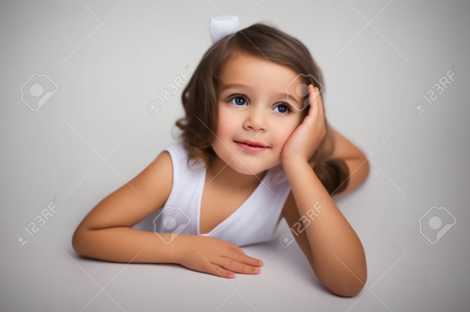 Little girl lying on the floor, looking up and dreaming on white  background