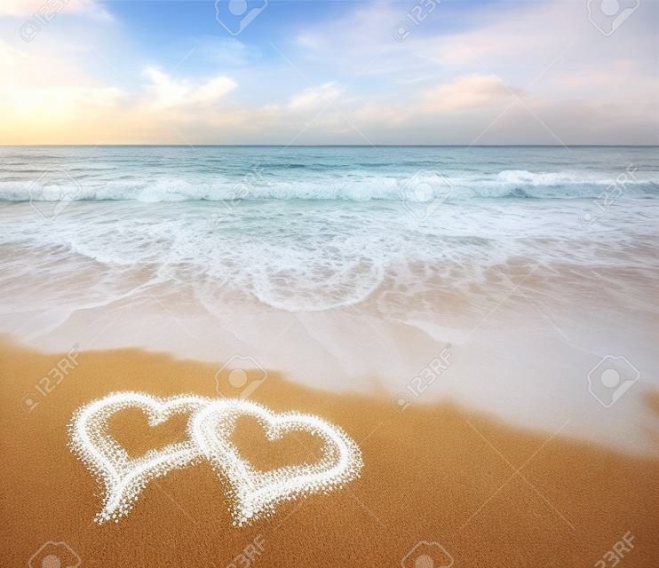Сердца нарисованные на песке пляжа.