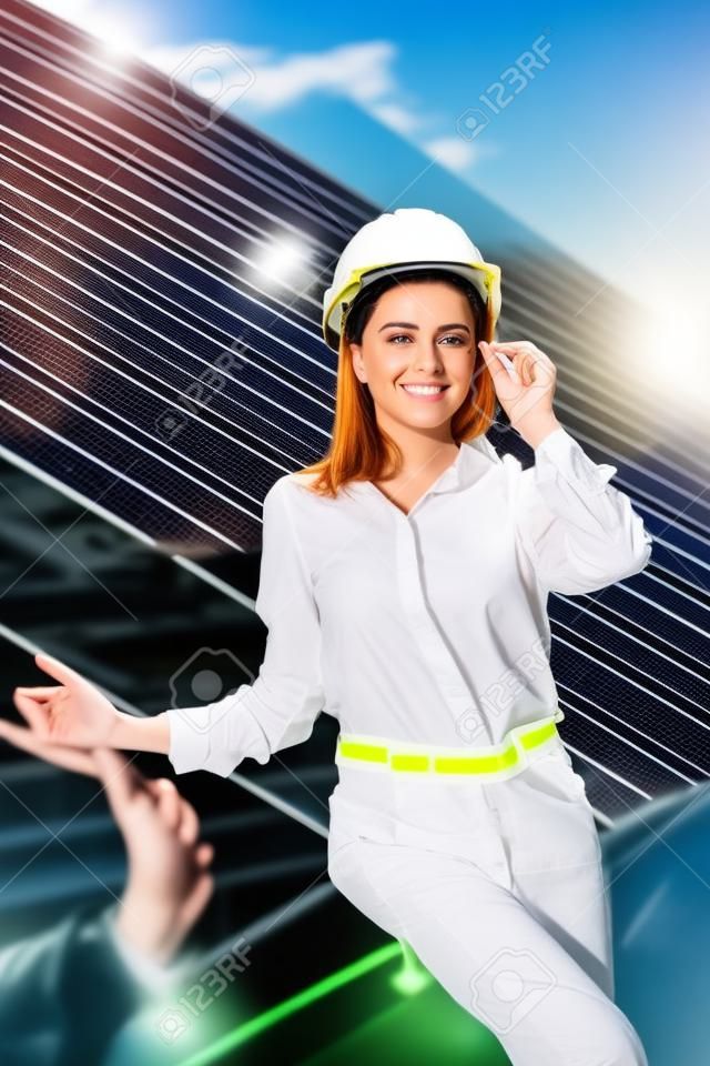 Beautiful young engineer standing near solar panels outdoors, Green Energy Concept.