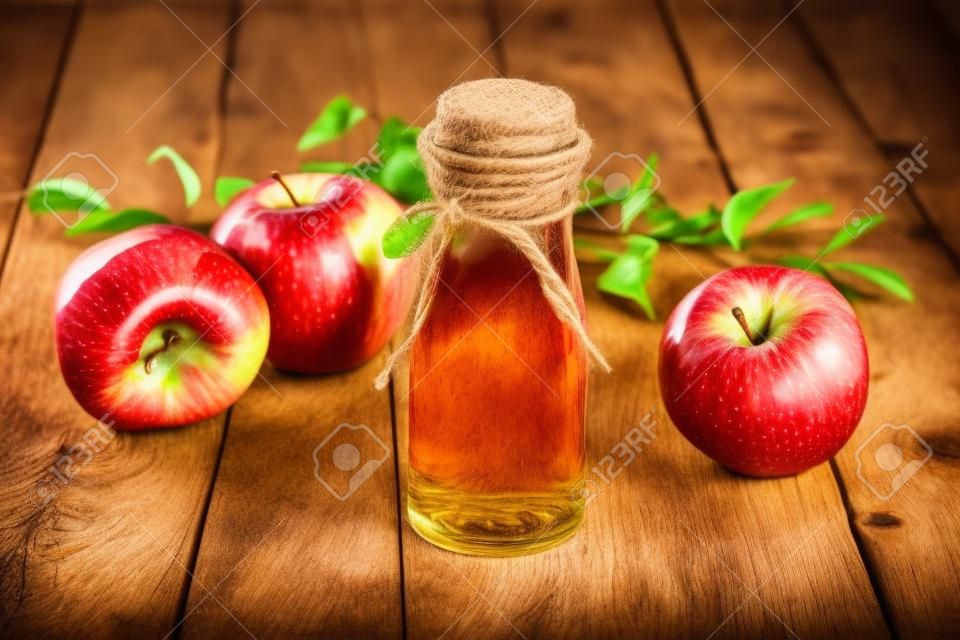 애플 사이다 식초와 소박한 나무 배경 위에 빨간 사과