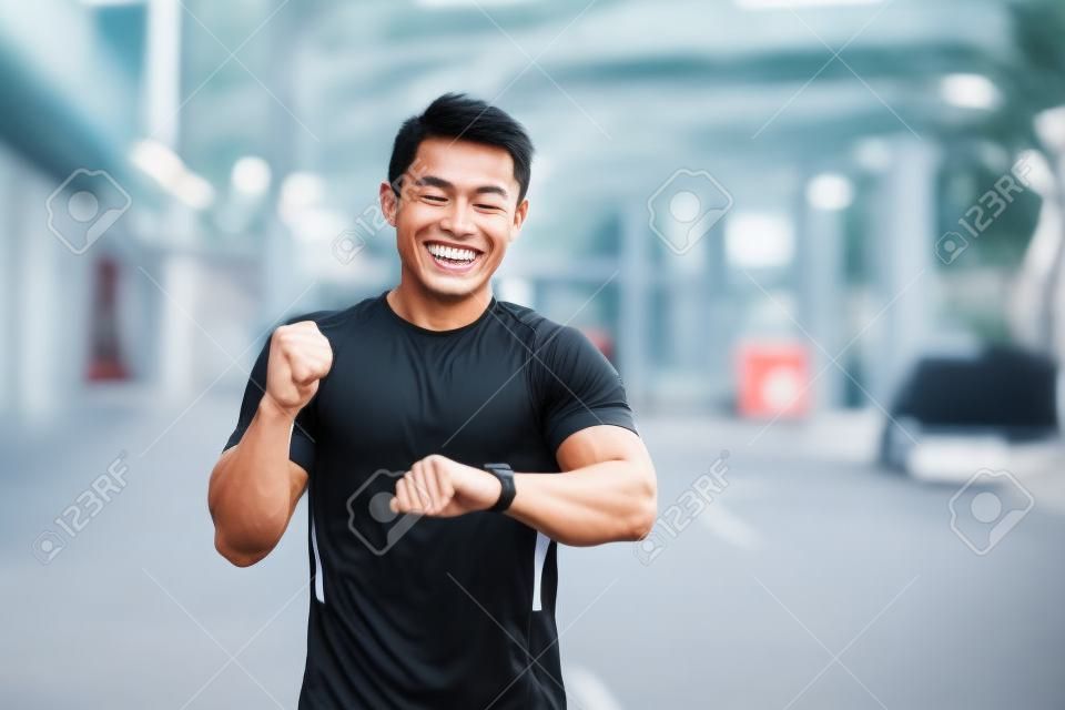 아침 달리기를 하는 남자 아시아 선수는 달성한 결과에 기뻐하고 미소를 짓습니다.