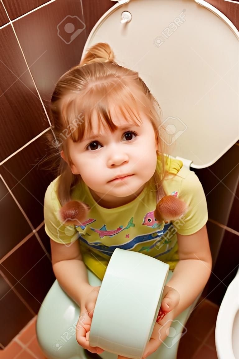 어린 소녀가 변기에 앉아있다.
