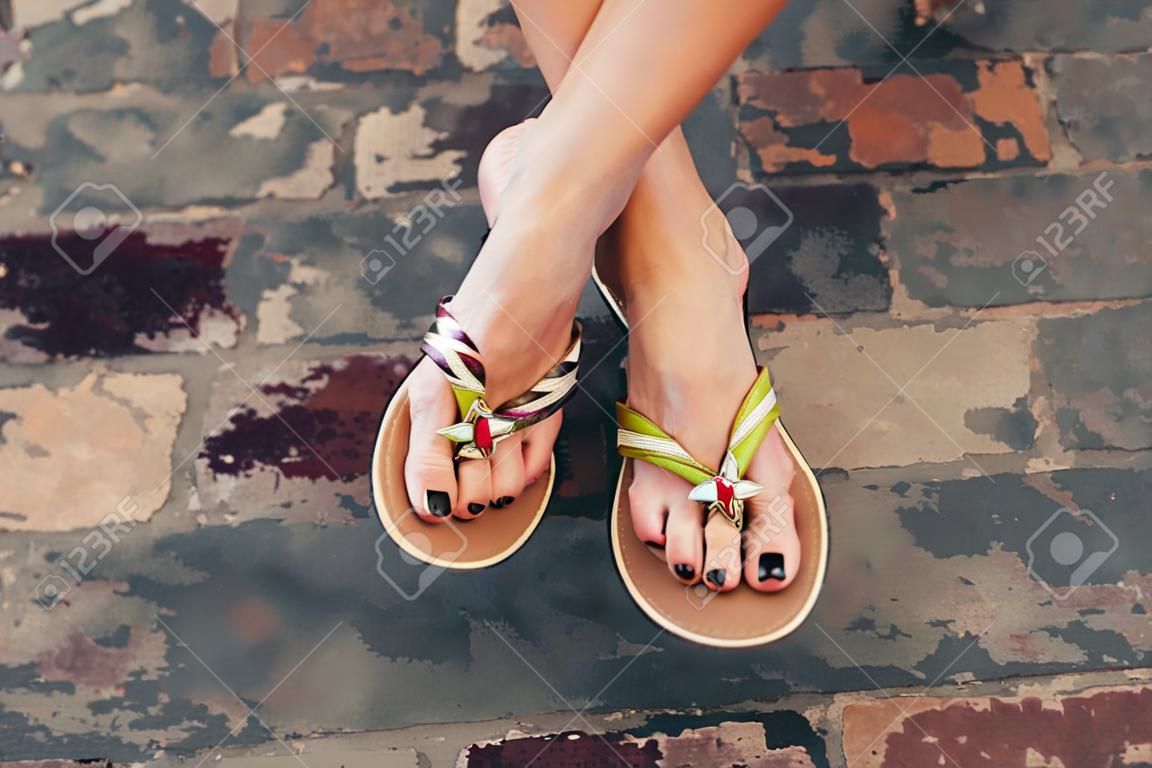 女人的腿在夏天的平底拖鞋戶外一天拍攝城市