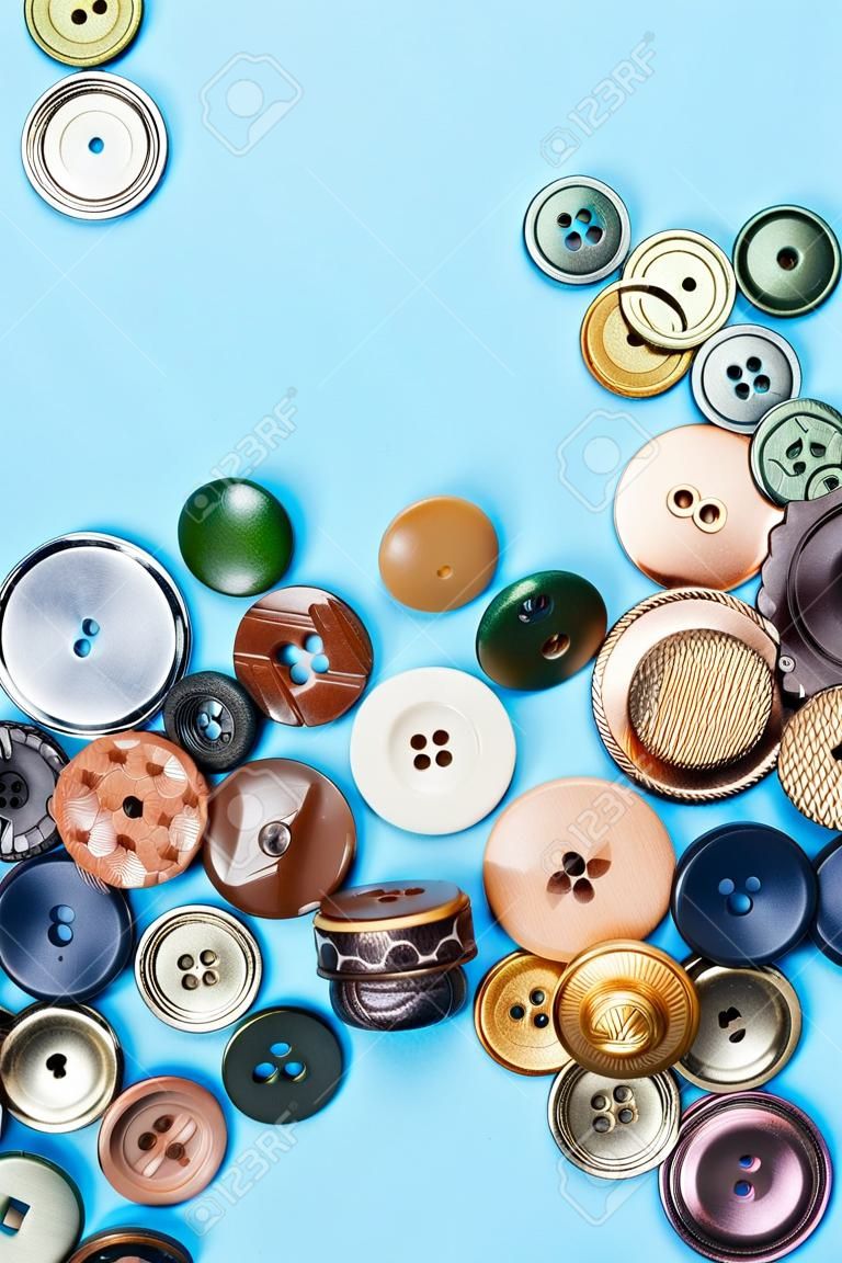 top view of pile of various buttons on blue background with blank copyspace