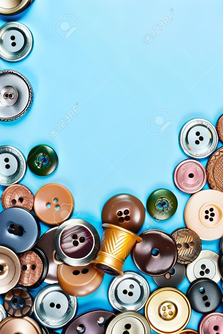 top view of pile of various buttons on blue background with blank copyspace