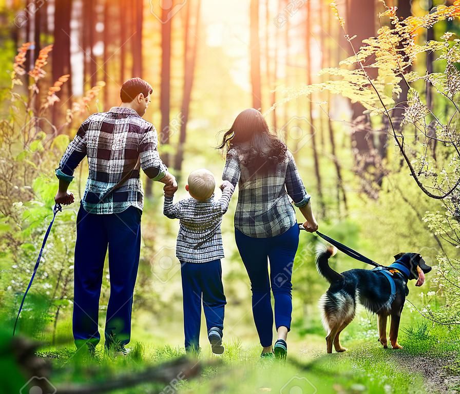 幸福的家庭與狗在林中行走