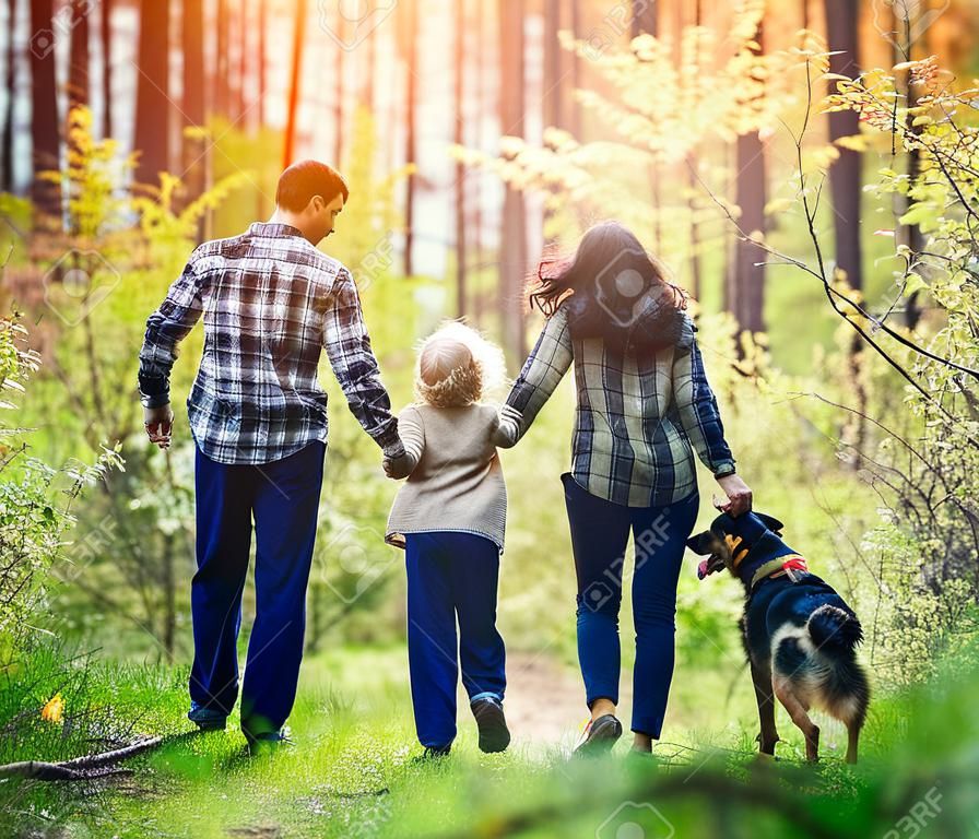 Heureuse famille marchant avec un chien dans la forêt