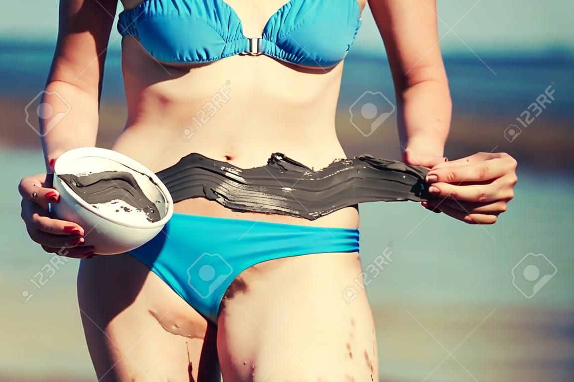 Frau , die Schlamm-Maske auf dem Körper am Strand