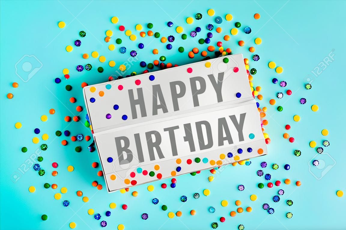 Caja de luz con texto feliz cumpleaños y coloridos chispitas de azúcar vista superior