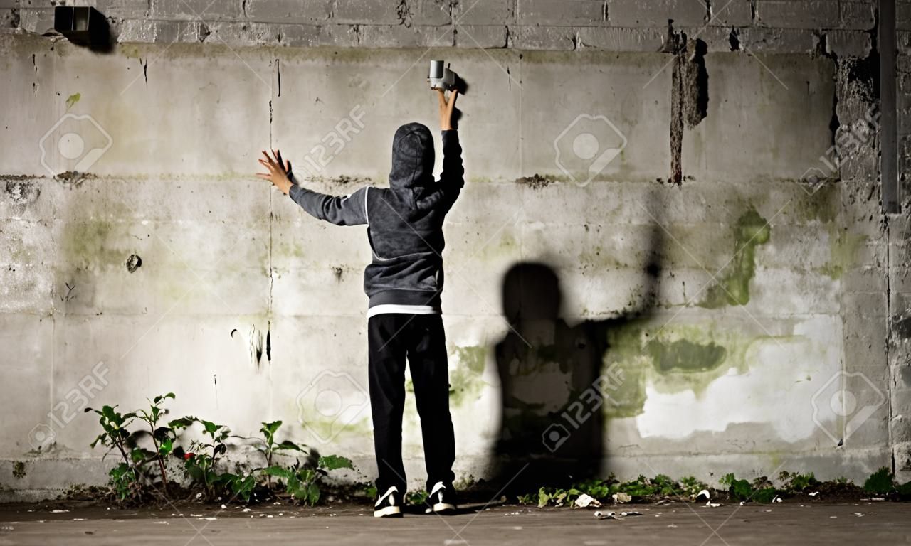 Jeune avec peinture aérosol et un mur de vide de graffiti
