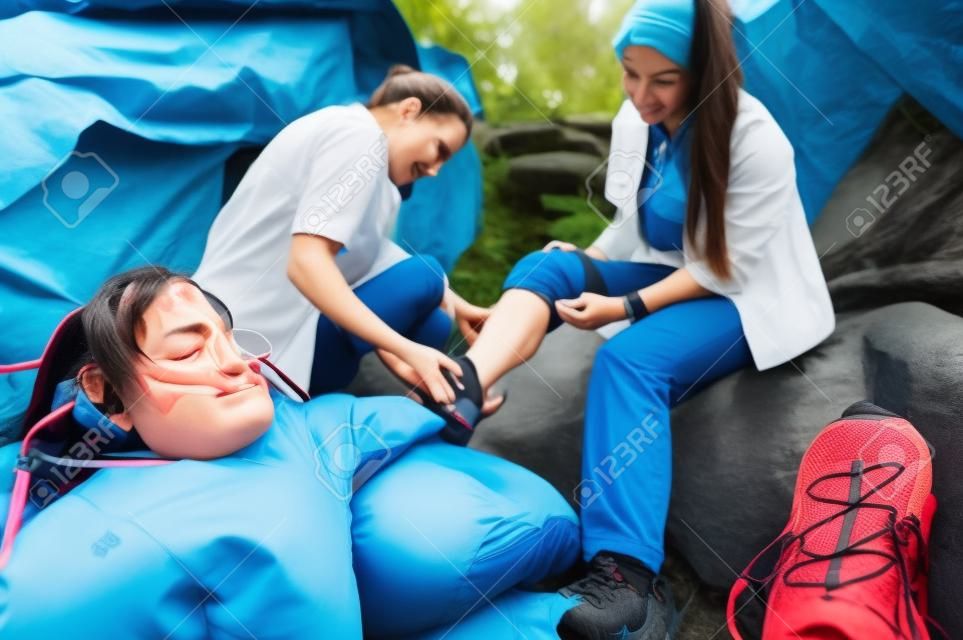 Una mujer ha torcido el tobillo durante una excursión, su amigo utiliza el kit de primeros auxilios para atender a la lesión