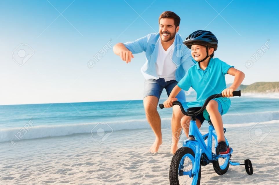 Baba ve oğul birlikte eğlenmek sahilde bisiklete binmek için öğrenme