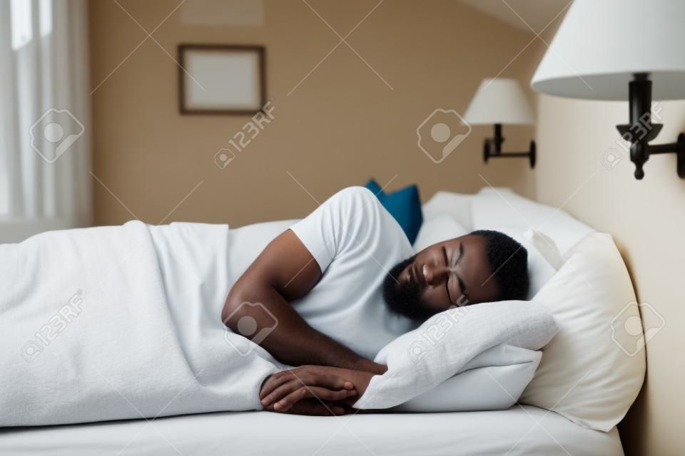 peaceful african black man sleeping comfortably in bed at home