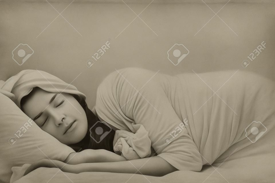 Una mujer que duerme con los brazos extendidos un poco fuera delante de ella.