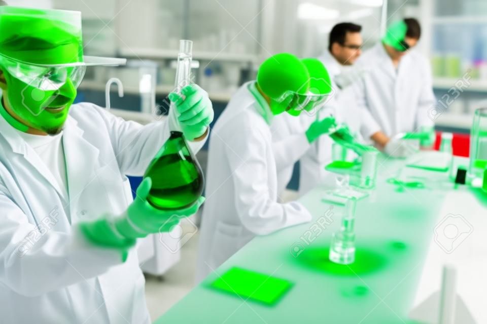 Chemists working in a laboratory and viewing the green liquid