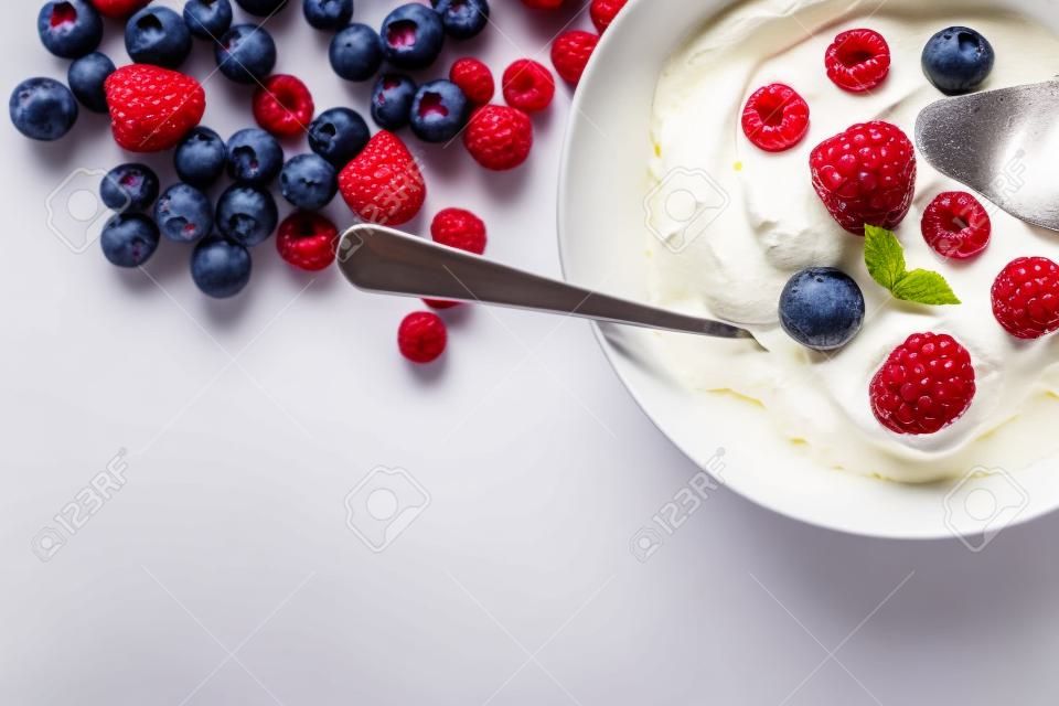 Dessert mit Beeren mit Sahne vor einem weißen Hintergrund