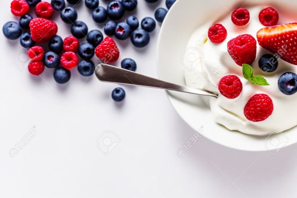 Dessert mit Beeren mit Sahne vor einem weißen Hintergrund