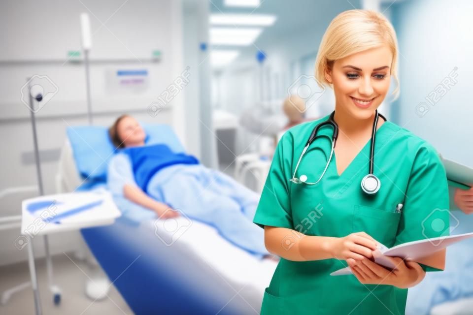 Nurse standing while looking at a clipboard in hospital ward