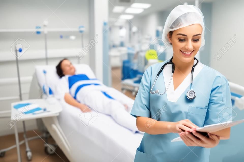 Nurse standing while looking at a clipboard in hospital ward