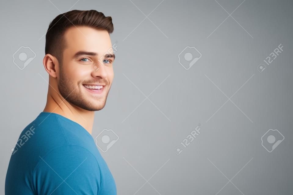 Portrait vue de côté de jeune homme souriant sur fond blanc