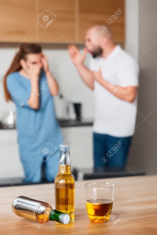 Angry couple arguing after drinking alcohol at home in the kitchen