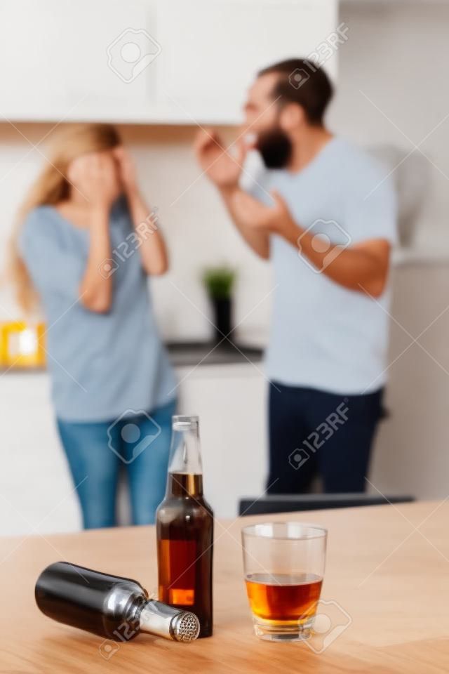 Angry couple arguing after drinking alcohol at home in the kitchen