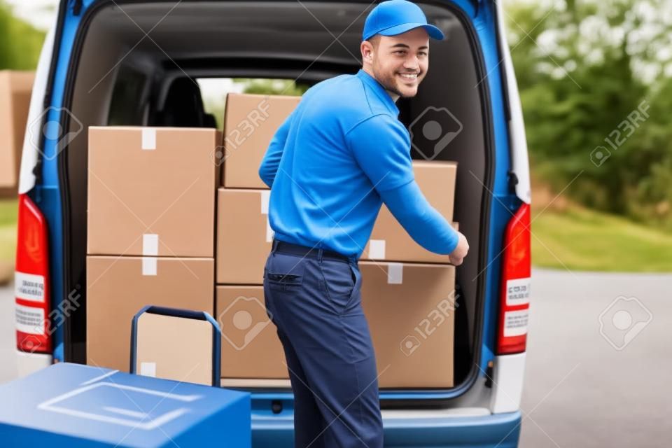 Driver di consegna caricando il furgone con scatole di fuori del magazzino