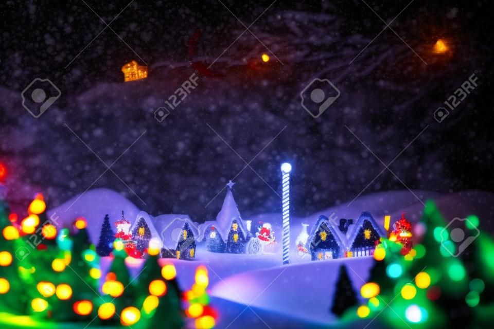 Silhouette of santa claus and reindeer against cute christmas village at north pole