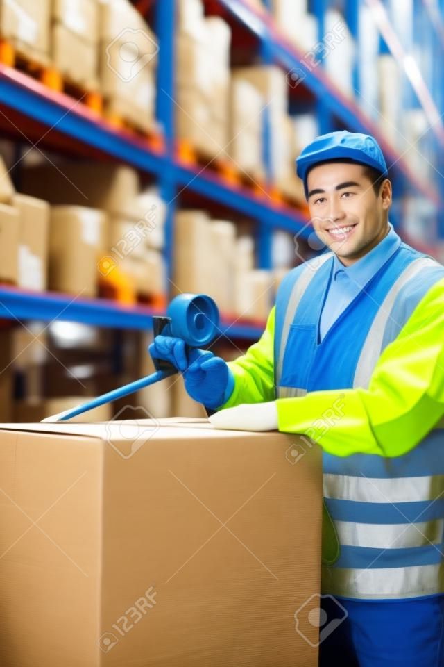 Warehouse worker sealing cardboard boxes for shipping in a large warehouse