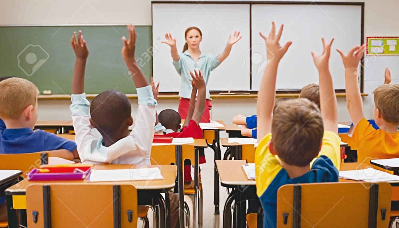 초등학교 수업 시간에 자신의 손을 올리는 학생들