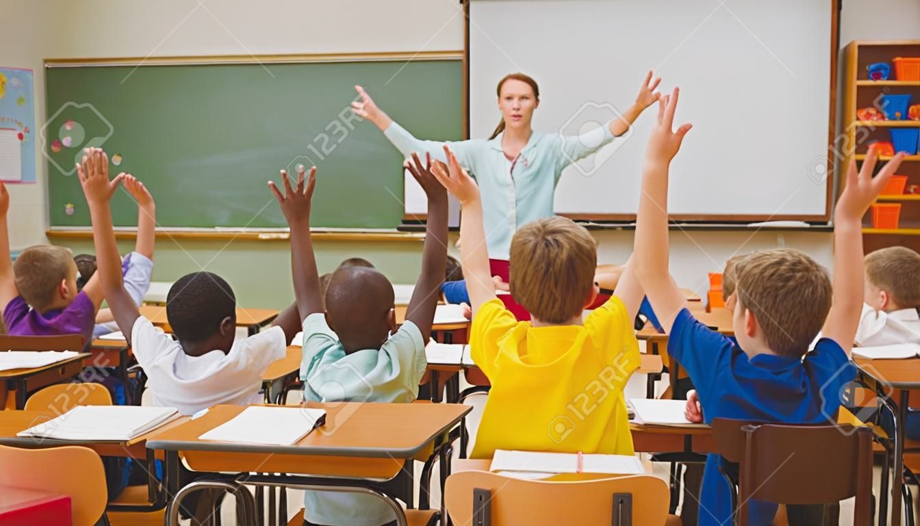 Les élèves qui élèvent leurs mains pendant la classe à l'école élémentaire